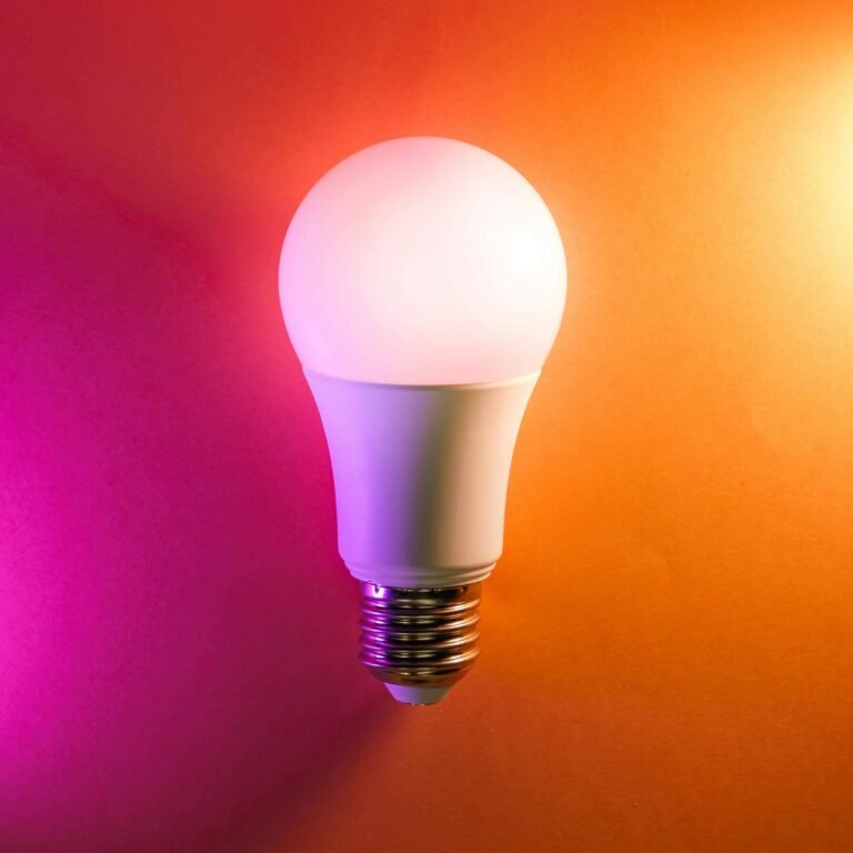 Illuminated smart light bulb on an orange background, showcasing its modern design and colorful lighting options for enhancing interior spaces.