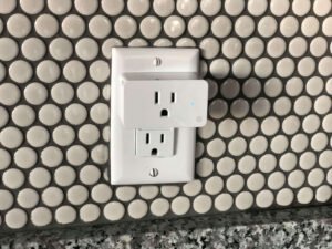 Smart plug installed in a wall outlet, showcasing the integration of technology into home decor and the convenience of remote device control for energy efficiency.