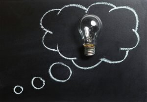 A light bulb with a thought bubble drawn on a blackboard
