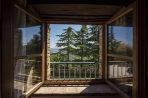 Experience the serene beauty of nature through this open window with a rustic home design. Discover how large windows can enhance natural light and bring outdoor views into your home.