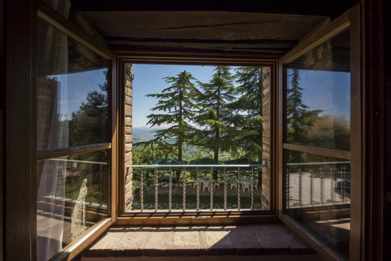 Experience the serene beauty of nature through this open window with a rustic home design. Discover how large windows can enhance natural light and bring outdoor views into your home.