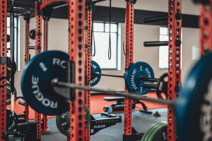 Gym interior with red power racks, blue weight plates, and Olympic bars