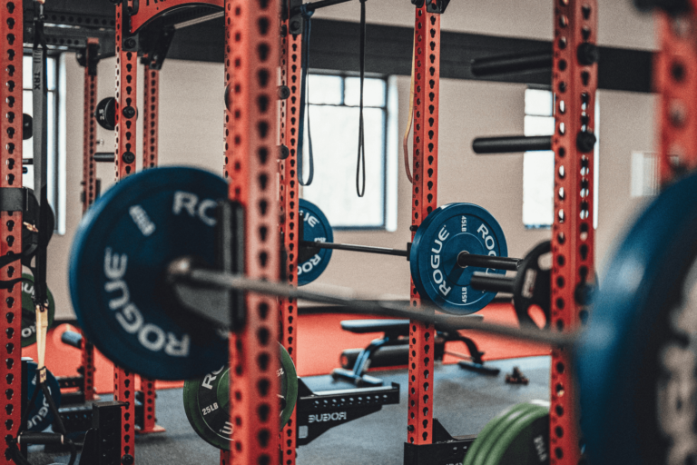 Gym interior with red power racks, blue weight plates, and Olympic bars