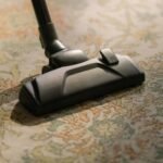 Close-up of a vacuum cleaner on a patterned carpet, highlighting vacuuming efficiency and home cleaning.