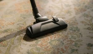Close-up of a vacuum cleaner on a patterned carpet, highlighting vacuuming efficiency and home cleaning.