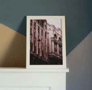 Framed photograph of ornate European architecture displayed on a white shelf against a multi-colored geometric wall background