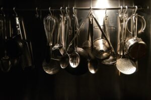 Metal cooking utensils suspended on a storage rack.