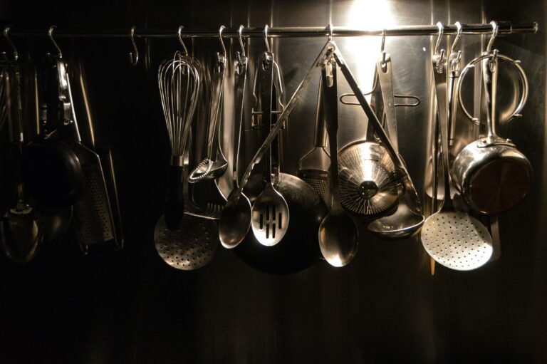 Metal cooking utensils suspended on a storage rack.