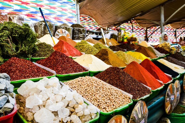Colorful piles of spices displayed in a busy market setting.