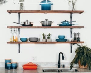 Kitchen shelves with vibrant pots and dinnerware against a light wall.