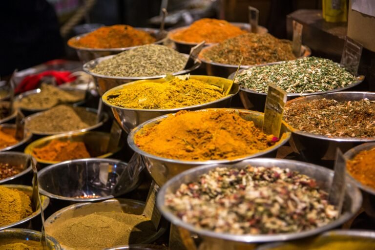 Selection of ground spices and seeds in metal bowls at a market stall.