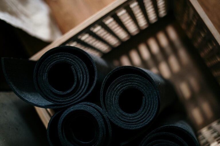 Rolled black standing desk mats arranged in a wooden crate