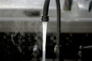 Modern faucet streaming water into a stainless-steel sink.