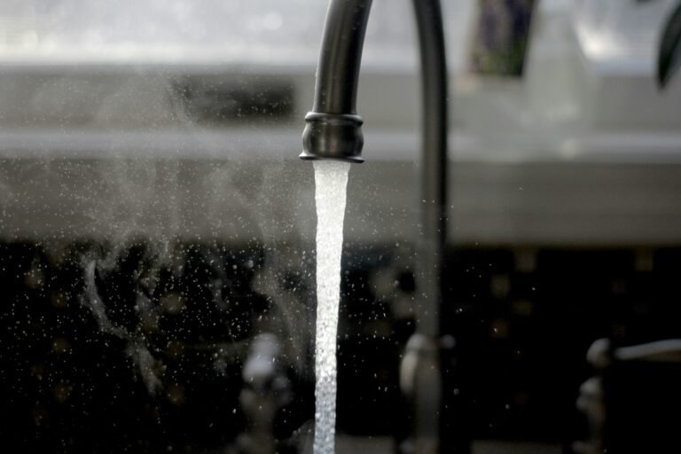 Modern faucet streaming water into a stainless-steel sink.