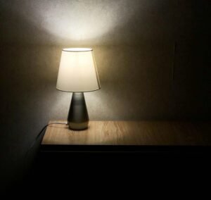 Table lamp on a wooden nightstand against a dark background