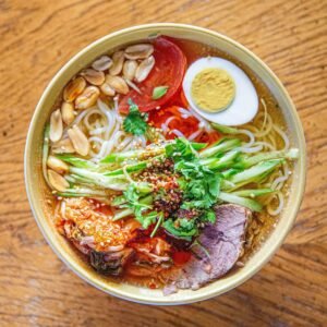 Bowl of ramen garnished with meat, egg, and vegetables