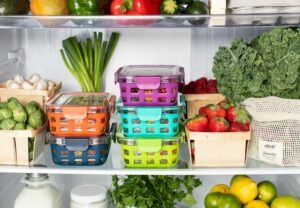 Fridge interior neatly stocked with fresh fruits and vegetables in containers.
