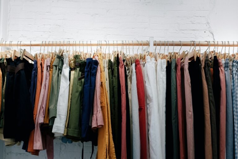 Row of stylish tops and dresses hanging on boutique hangers.