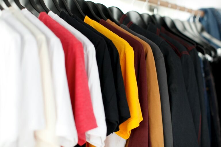 Multiple colored T-shirts hanging in a row.