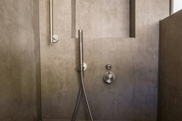 Minimalistic bathroom shower with concrete-look walls and chrome fixtures