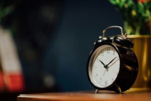 Vintage metal clock with a round face, set on a rustic wooden table.