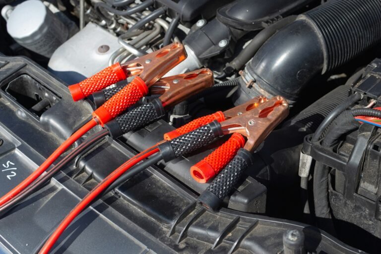Jumper cables attached to a vehicle battery in an engine bay.