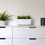 Minimalist white dresser topped with small potted greenery