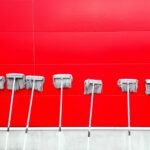 Several gray mop heads leaning in a row on a bright red background.