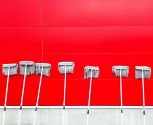 Several gray mop heads leaning in a row on a bright red background.