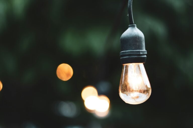 Vintage-style pendant light glowing in an outdoor setting.