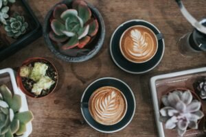 Cup of latte art on a wooden tray surrounded by succulents