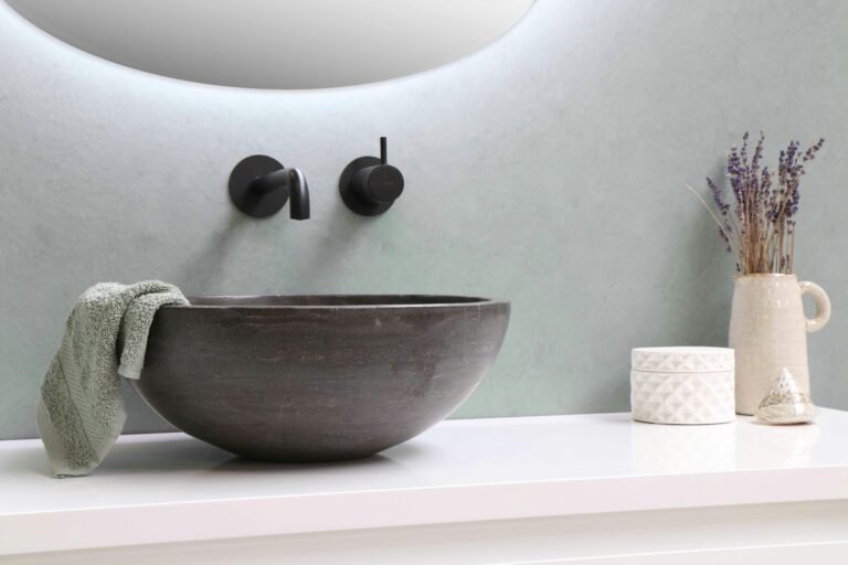 Rounded bathroom sink with a matte finish next to a wall-mounted faucet.