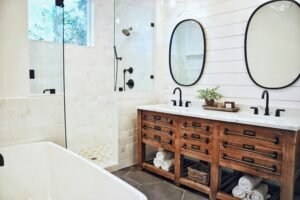 Modern bathroom with wooden vanity, round mirrors, and sleek black fixtures.