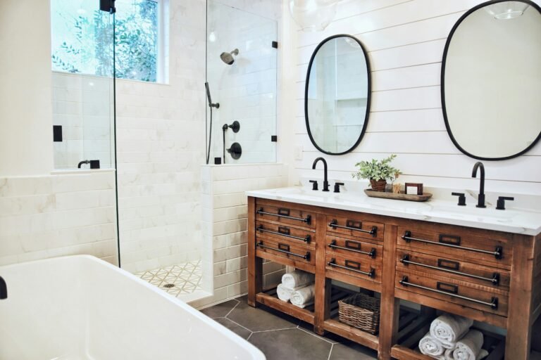 Modern bathroom with wooden vanity, round mirrors, and sleek black fixtures.
