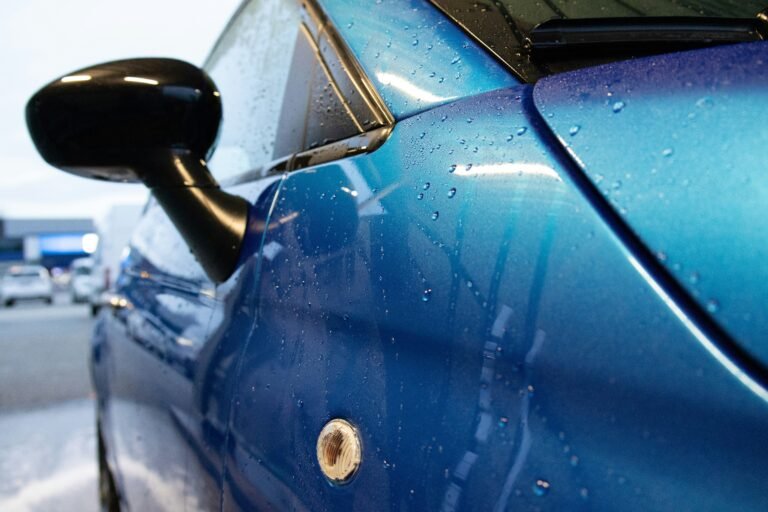 Shiny blue car door spotted with raindrops.