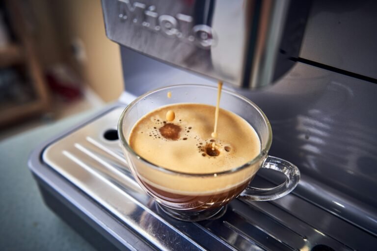 Foamy espresso shot being prepared under a cafe machine spout.
