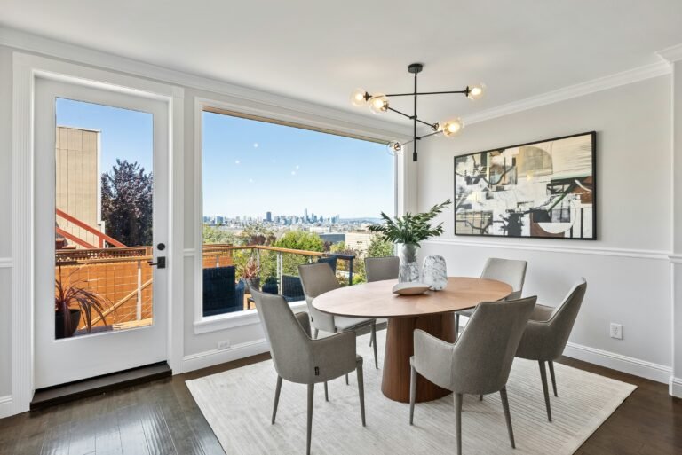 Bright dining room with large windows, modern chandelier, and scenic view.