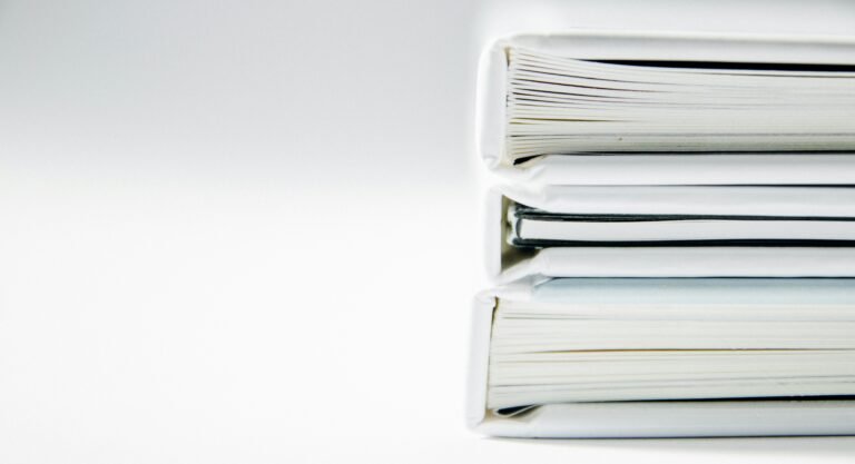 Neatly bound documents stacked on a white surface.