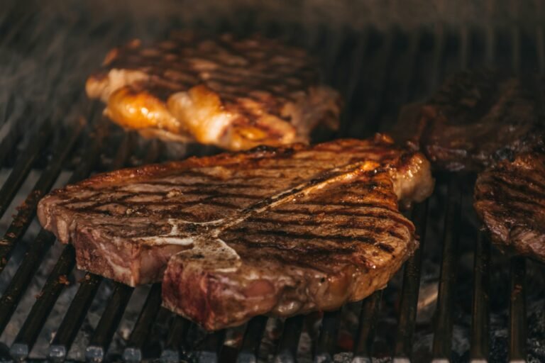 Juicy steaks cooking over open flames on a grill.