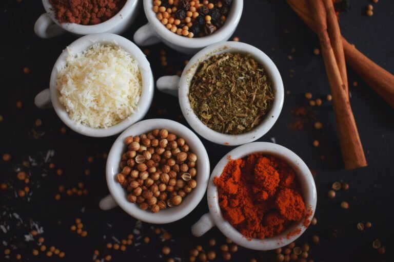 Assorted spices in white ramekins on a light background.