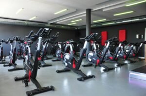 Row of stationary bikes in a brightly lit gym.