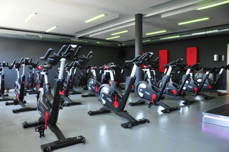 Row of stationary bikes in a brightly lit gym.