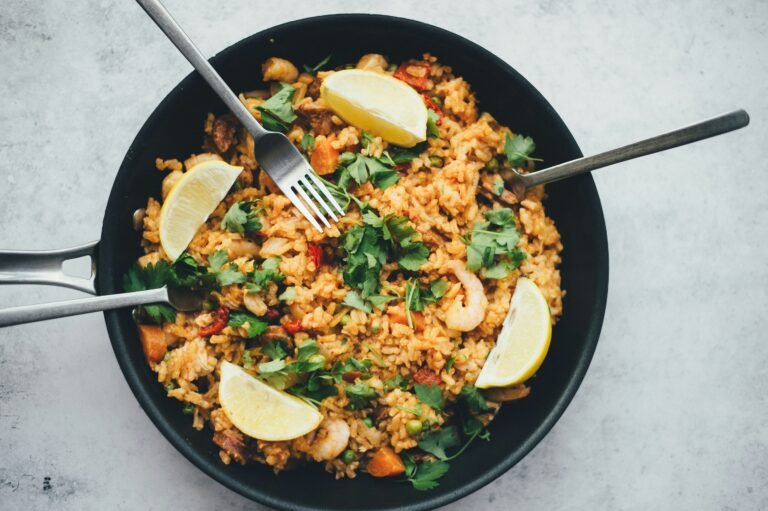 Savory rice and vegetable meal garnished with herbs in a black skillet.