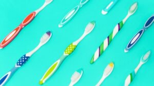 Brightly colored toothbrushes aligned on a turquoise background.