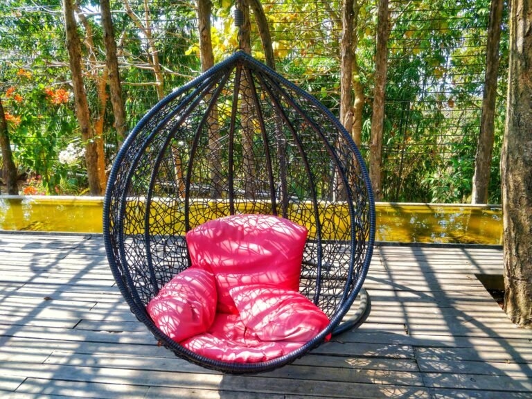 Hanging egg-shaped wicker chair with plush red cushions